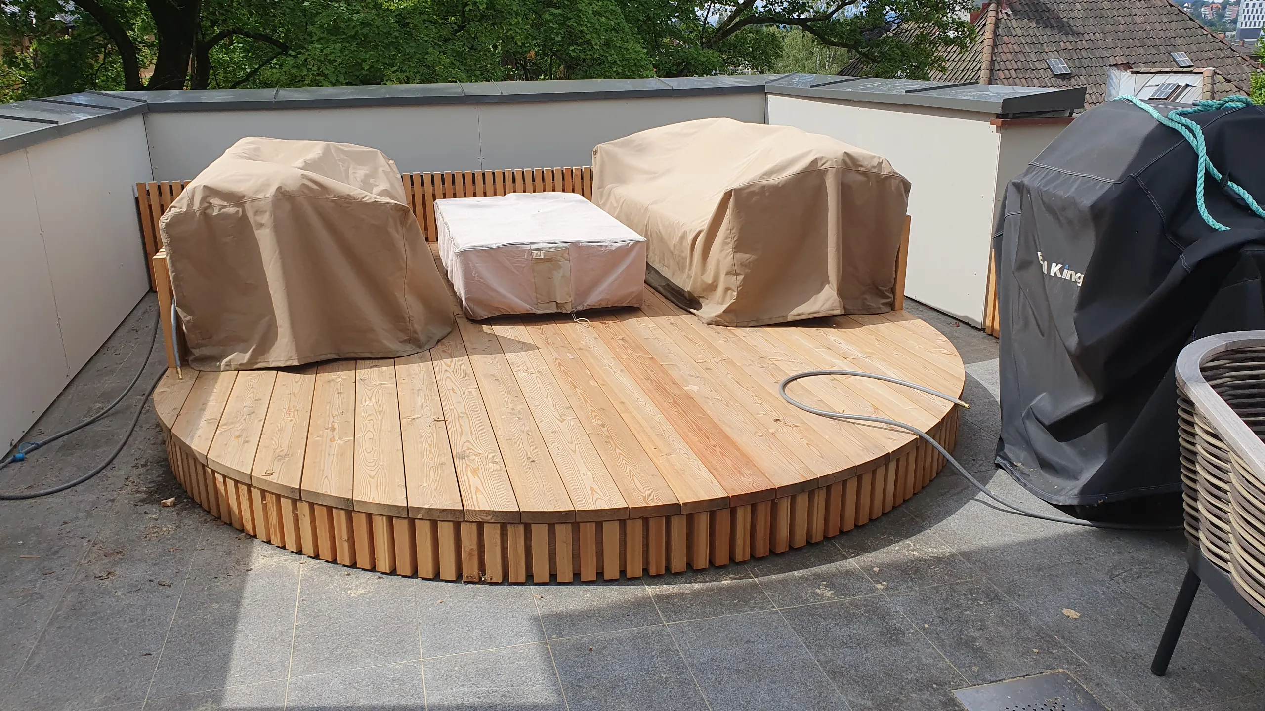 Terrasse med treplater og møbler dekket med beige trekk